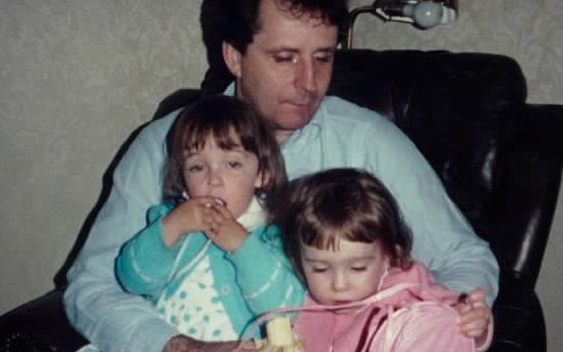 Doug holding both of the twins. Kirsten eats half a banana while Chelsi plays with a purse.