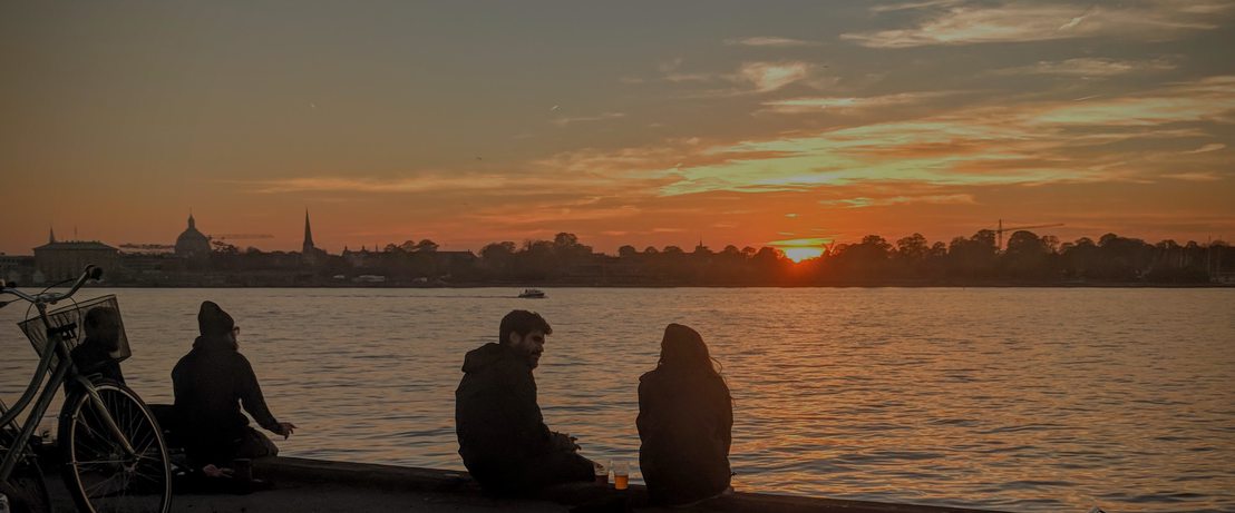 Sunset at Mikkeller Baghaven with a couple silhouetted. The city skyline can be seen behind.