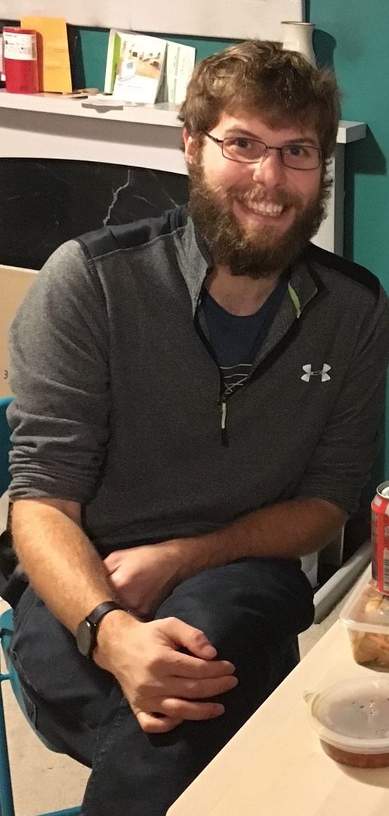 Guy seated at a table with glasses and a short beard