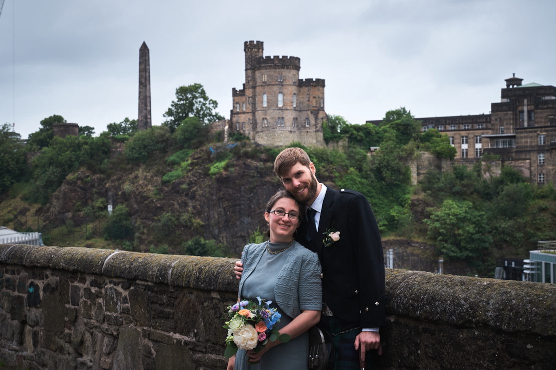 Chelsi and Guy posing in front of the obelisk and the old jail on Calton Hill.