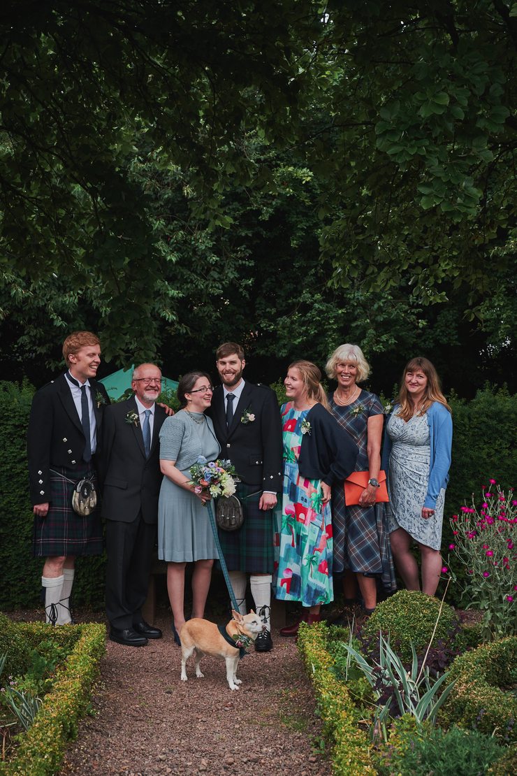 A group shot of those present at the ceremony between the flowerbeds.